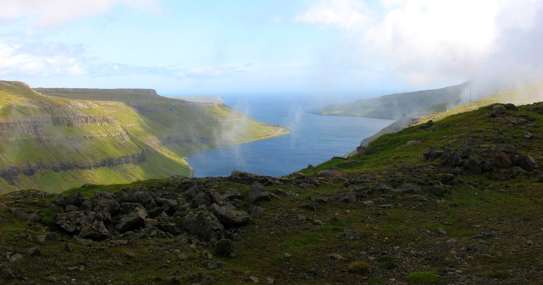 Blick auf steil abfallende Küstenhügel und dem azurblauen Wasser des ruhigen atlantischen Ozeans.