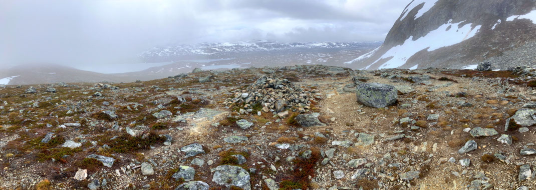 Sehenswürdigkeiten Kilpisjärvi - Dreiländereck: Ein Wanderweg führt über einen Hügelrücken zu einem Aussichtspunkt. Von dort aus lassen sich die Schneefelder auf den umliegenden Bergen und zwei Seen erkennen.