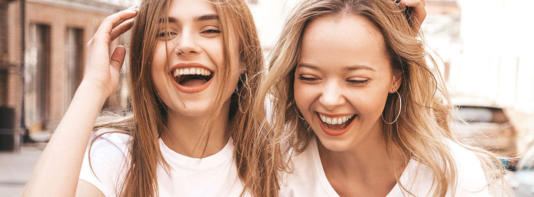 Zwei junge blonde Frauen lachen ausgelassen