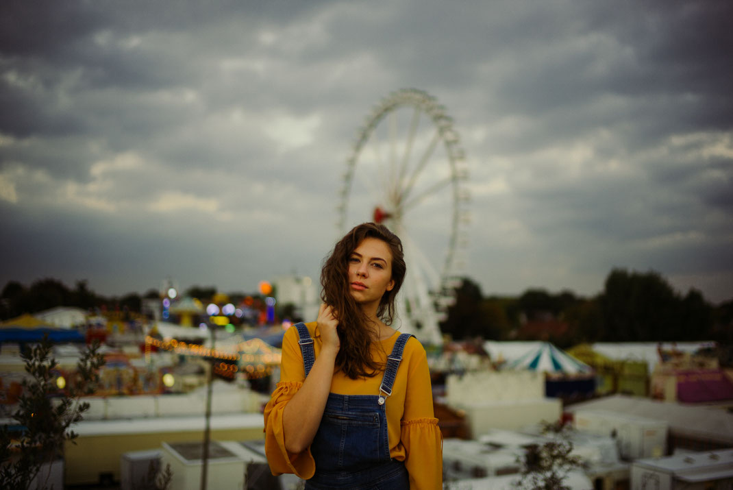 Junge Frau mit locken blickt in die Ferne im Hintergrund der Oldenburger Kramermarkt als Fotoshooting Location