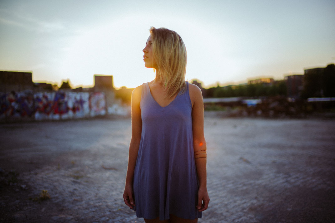 Frau mit Kleid schaut bei Sonnenschein in den Himmel