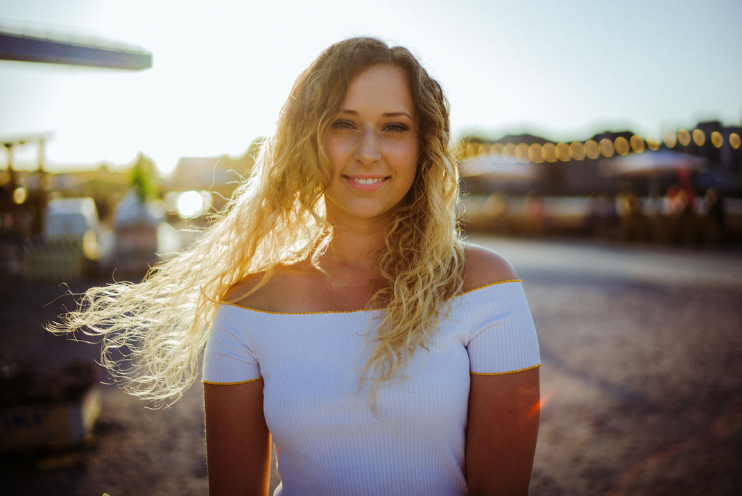 Junge Frau in sommerlichen Outfit blickt in die Kamera
