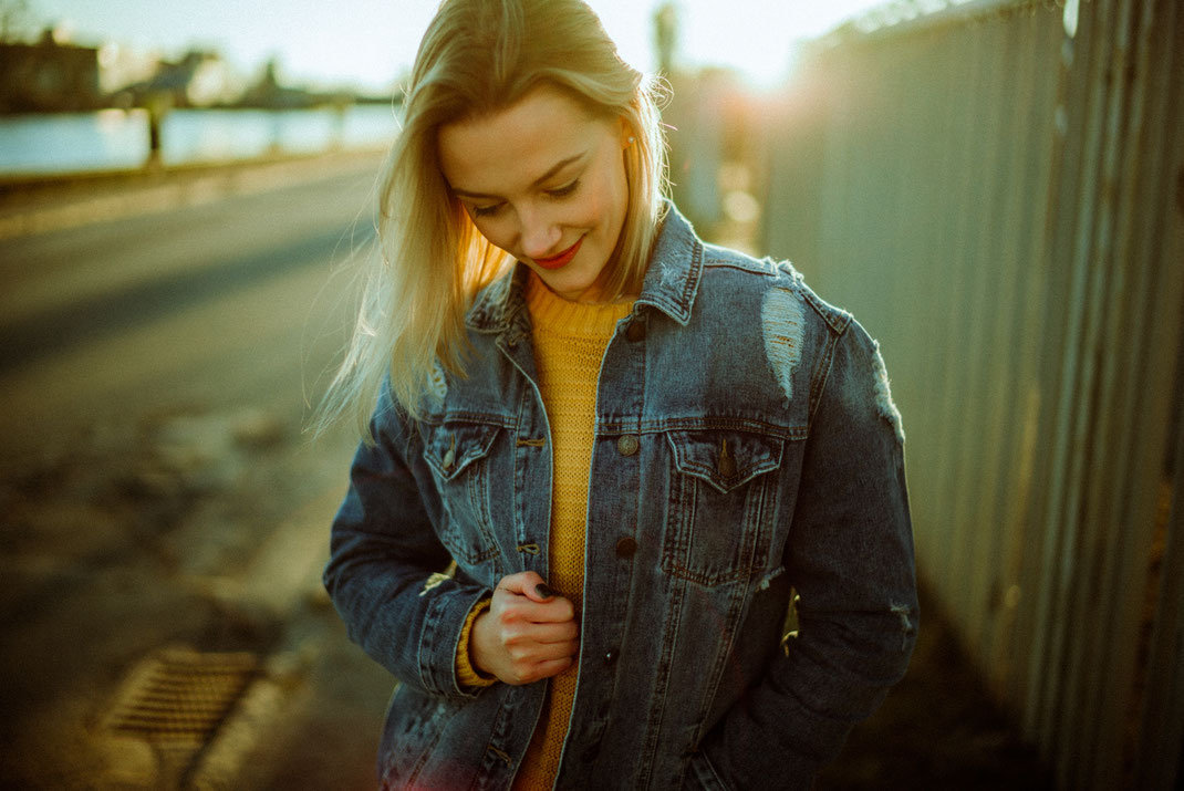 Junge Frau in Jeansjacke blickt nach unten