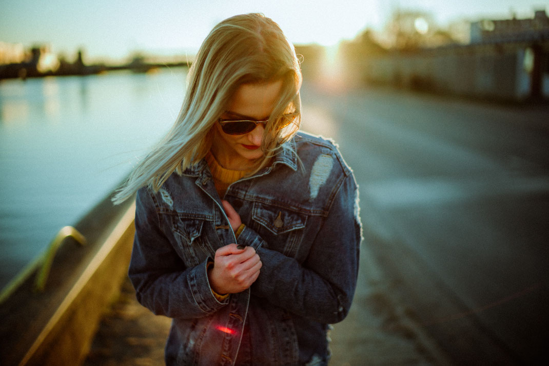 Frau mit Sonnenbrille klammert sich an ihre Jeansjacke