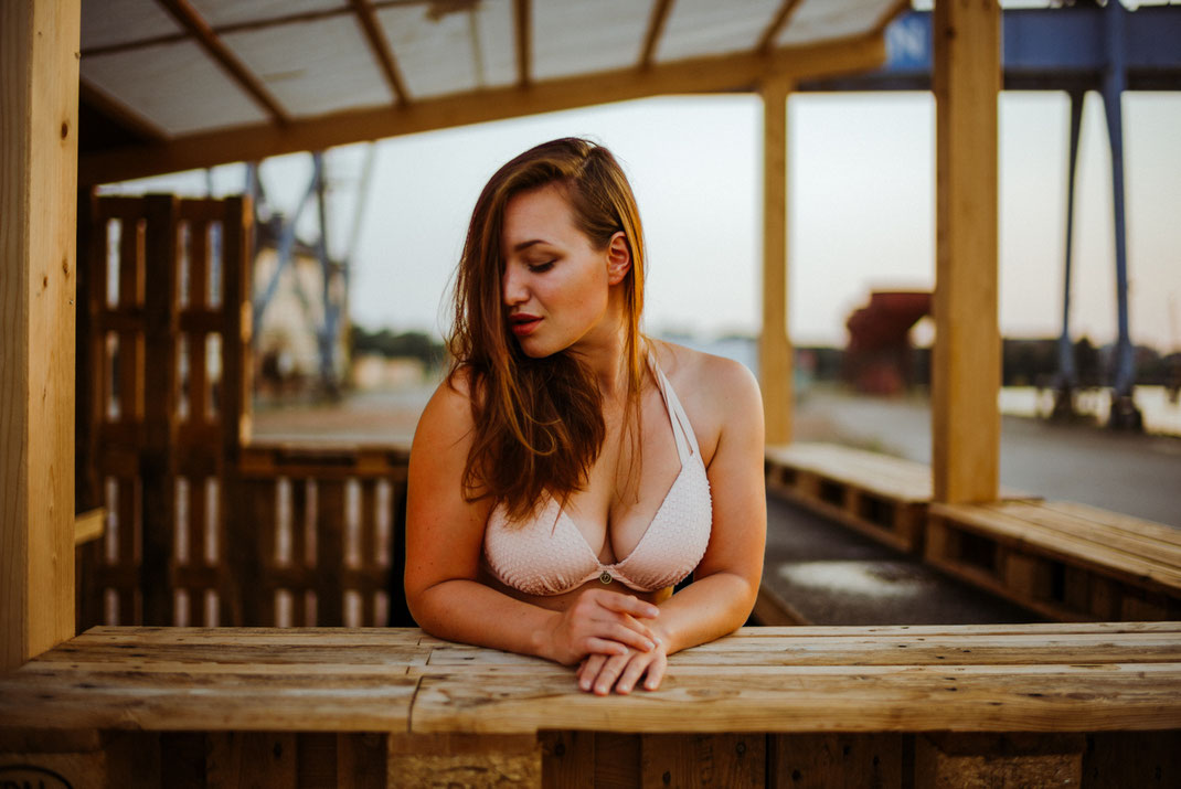 Frau in Bikini steht in einer offenen Holzhütte am Oldenburger Hafen