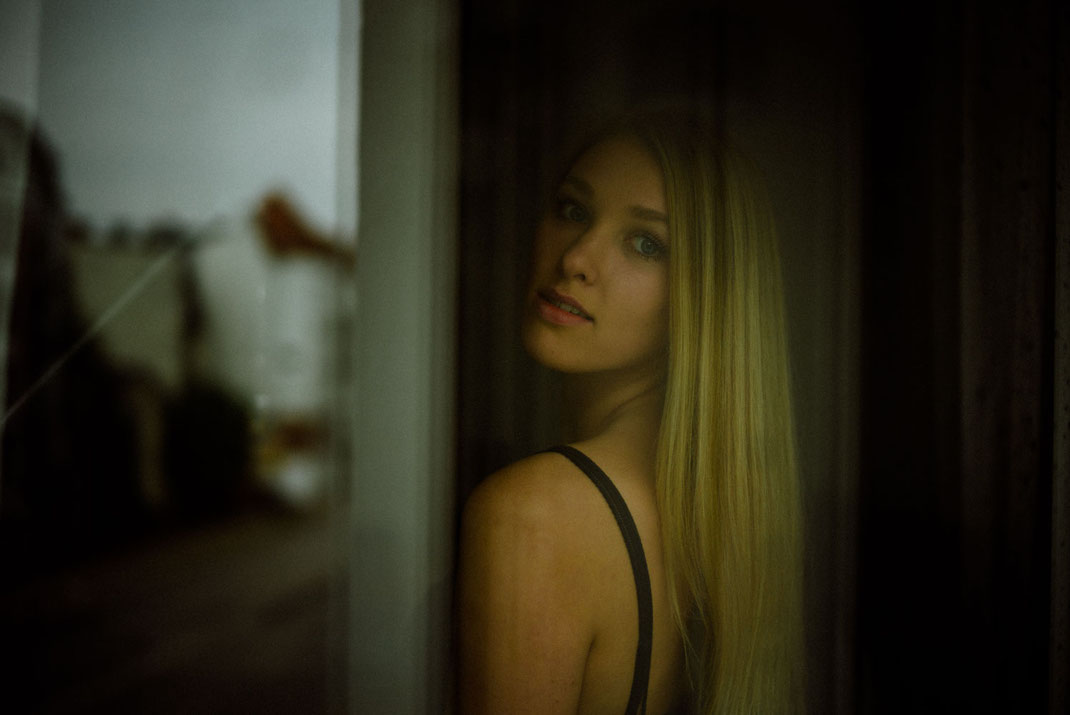 Frau mit blonden Haaren blickt aus dem Fenster
