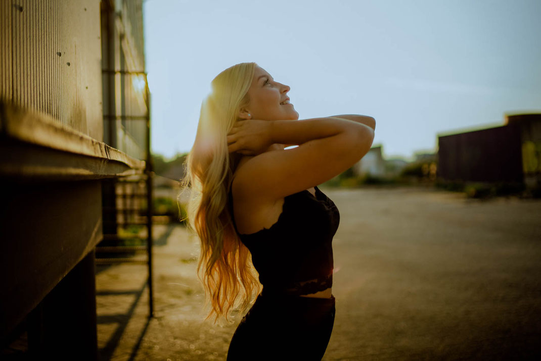 Junge Frau mit langen Haaren schaut in den Himmel und lächelt