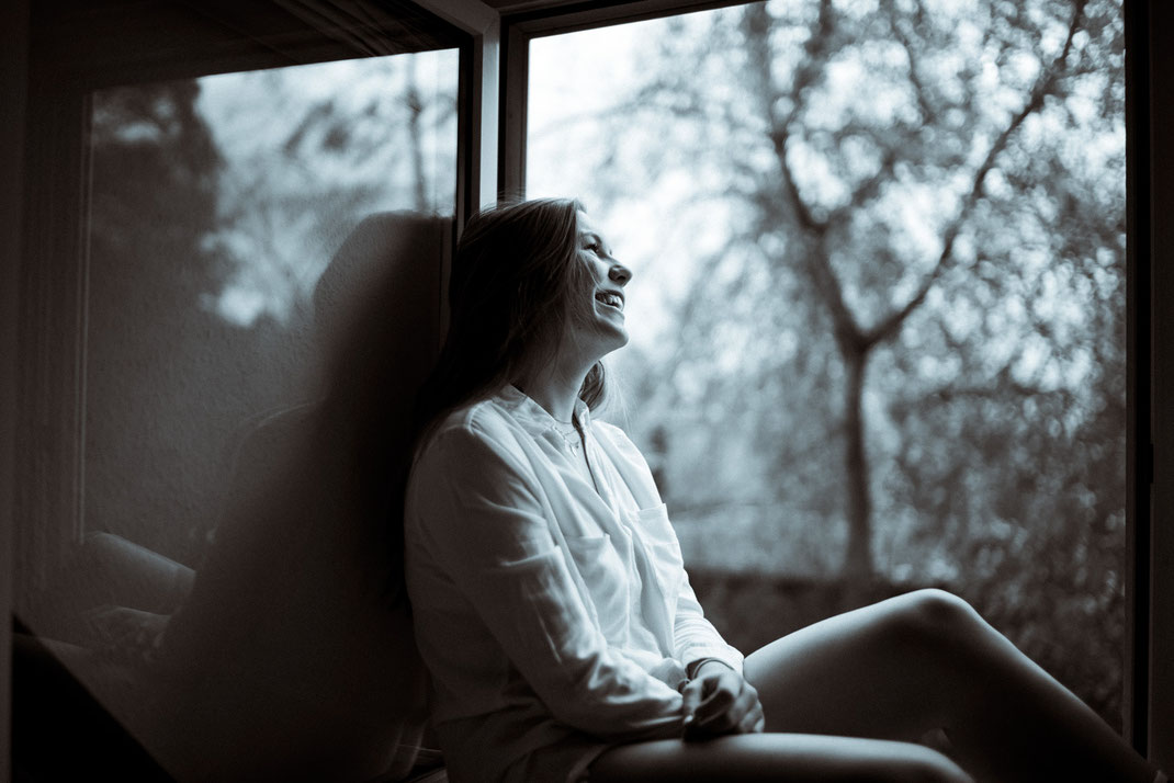 Junge Frau sitzt beim Fotoshooting am Fenster in Oldenburg