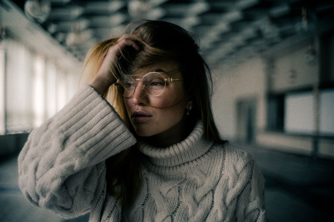 Model mit cooler runder Brille blickt Richtung Fenster