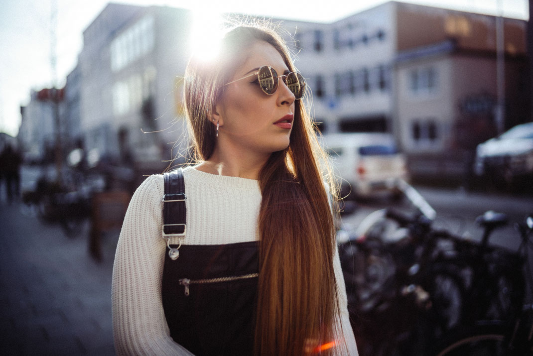 Junge Frau mit Latzhose und Sonnenbrille Gegenlicht und Lensflare