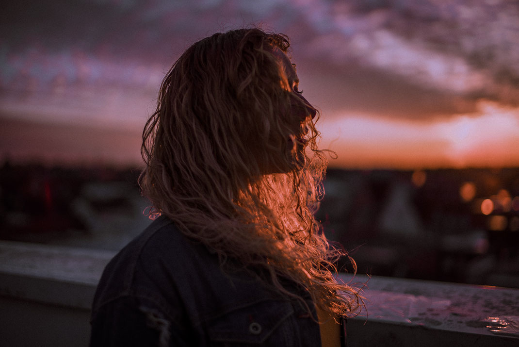 Haare bedecken das Gesicht einer jungen Frau Sonnenuntergang im Hintergrund
