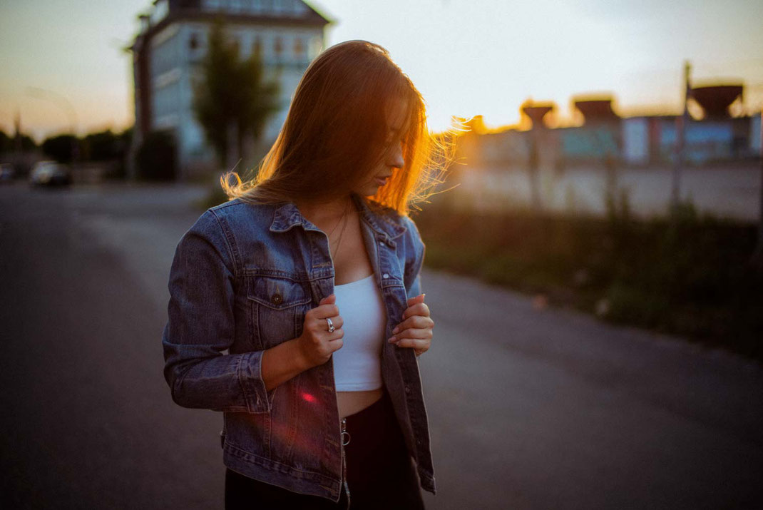 Junge Frau mit Jeansjacke im Gegenlicht