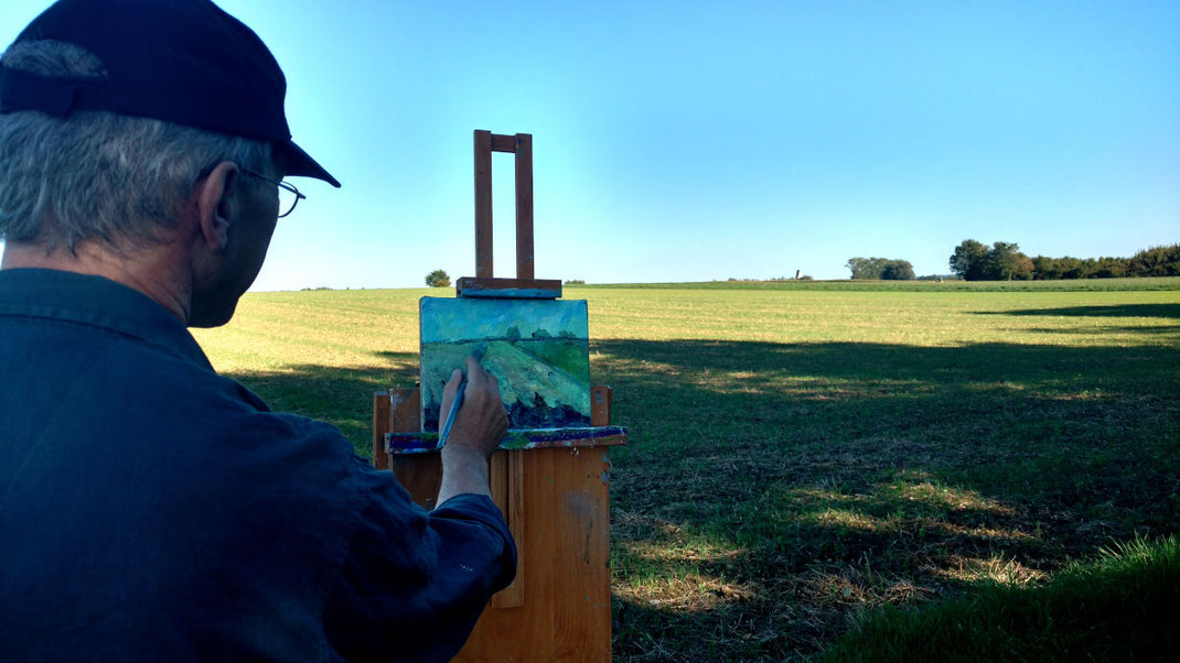 Pleinairmalerei. Ölbild auf der Staffelei, man sieht mich von hinten beim malen. Landschaft mit Wiese und Bäumen