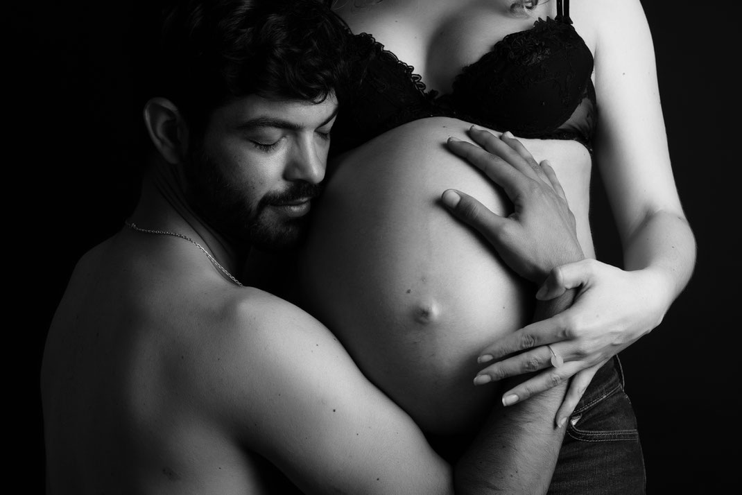 couple posant lors d'un shooting photo grossesse. Gros plan ventre en clair obscur