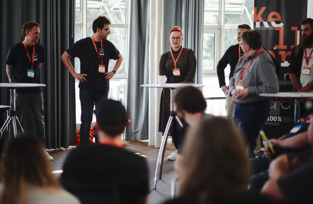 Event Foto vom BAR-CAMP 2022 der KELLERKINDER: Eine Gruppe von Teilnehmenden steht im Workshopraum vor einem Publikum. Im Hintergrund hängt ein großes Banner mit dem Kellerkinder-Logo.