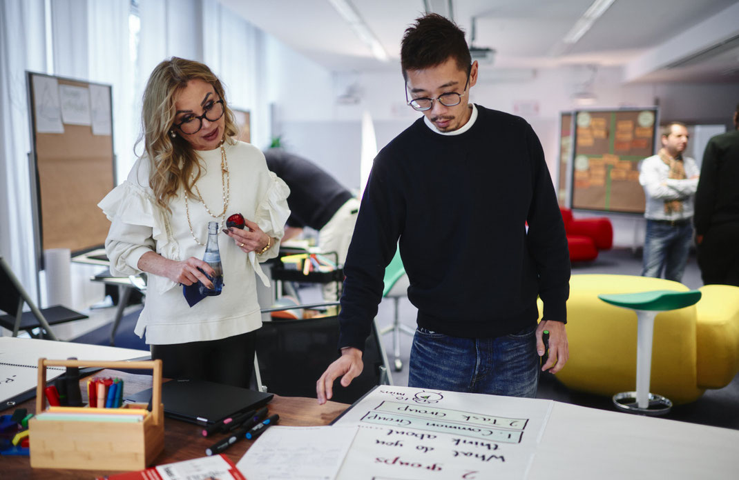 Event-Foto vom Mercedes-Benz Global Training in Stuttgart: Zwei Teilnehmende besprechen ihre Ergebnisse an einem Kreativtisch mit Markerbox und Flipchart.