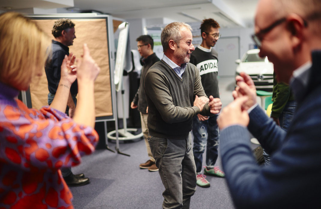 Event-Foto vom Mercedes-Benz Global Training: Die Teilnehmenden befinden sich mitten in einer dynamischen Gruppenübung. Es wird gelacht, diskutiert und mit vollem Körpereinsatz gearbeitet – ein Moment voller Energie und Teamgeist.