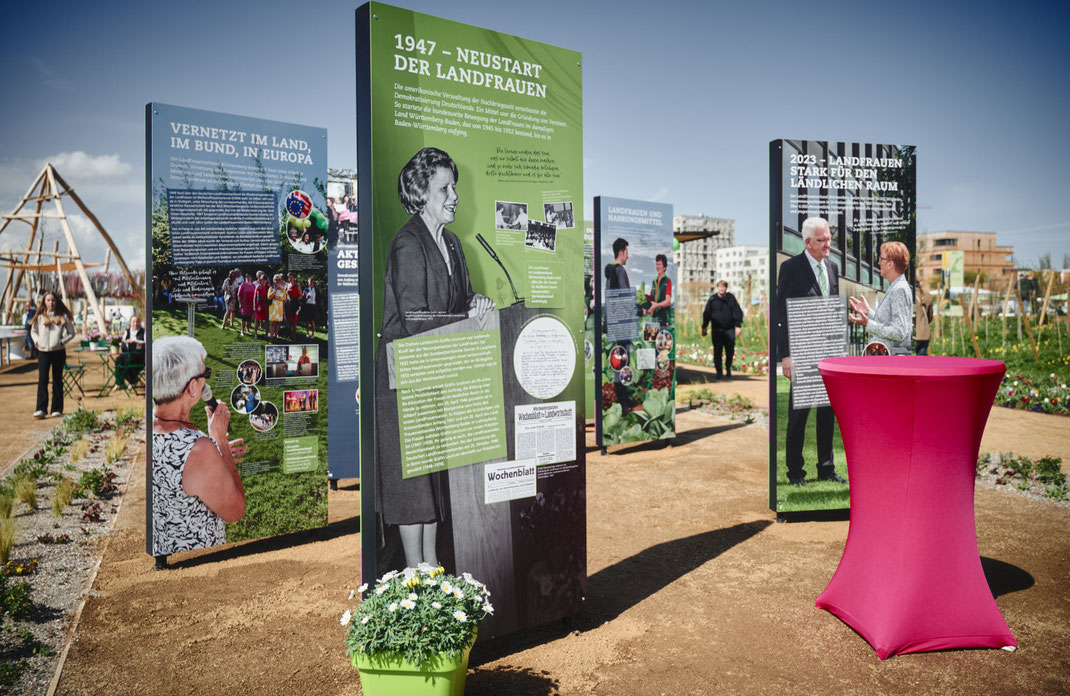 Eventfoto von Christoph Bastert: Ausstellungstafeln der LandFrauen Württemberg-Baden auf der BUGA Mannheim 2023 mit historischen und aktuellen Themen, im Außenbereich bei sonnigem Wetter.