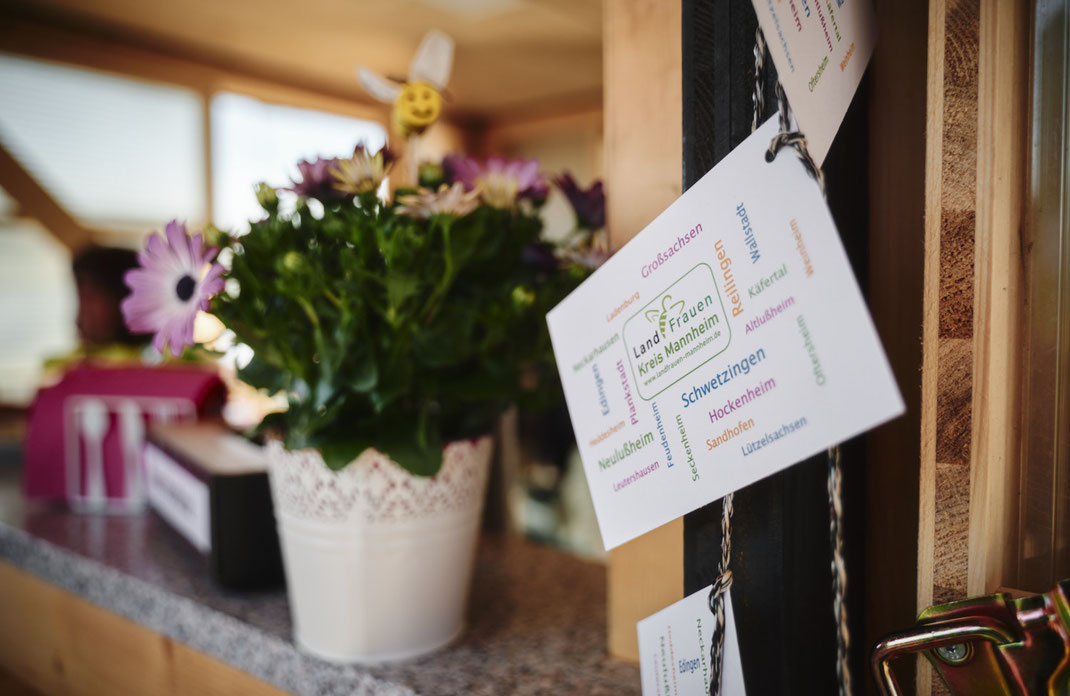 Eventfoto von Christoph Bastert: Dekorativer Stand der LandFrauen Kreis Mannheim auf der BUGA Mannheim 2023 mit Blumenschmuck und Infokarte.
