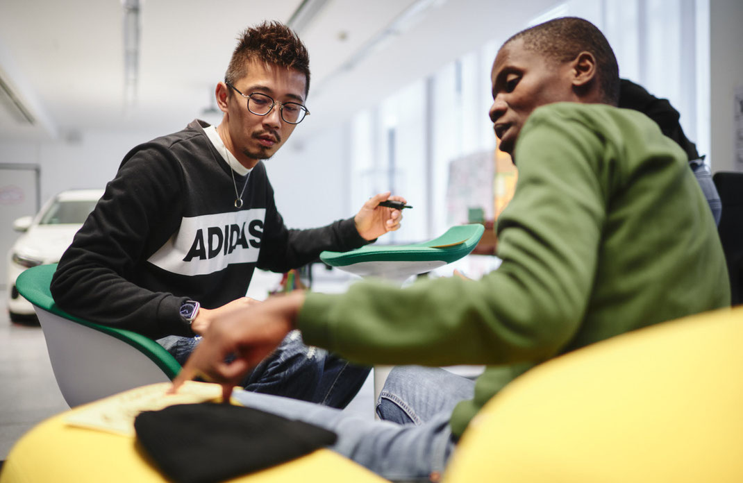 Event-Foto vom Mercedes-Benz Global Training: In konzentrierter Haltung besprechen zwei Teilnehmer ihre Notizen – der Austausch ist Teil der Gruppenarbeit, bei der Perspektiven und Eindrücke gesammelt werden.