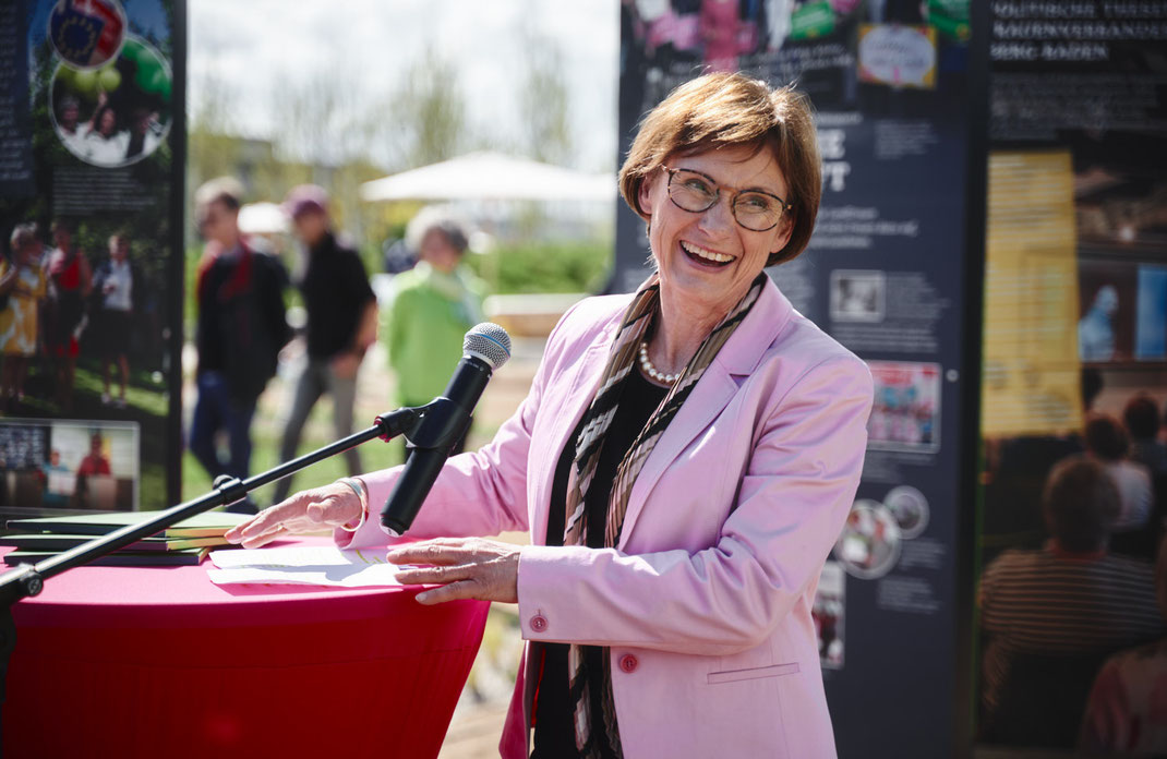 Eventfoto von Christoph Bastert: Rednerin mit Mikrofon bei einer Ansprache auf der LandFrauen-Veranstaltung auf der BUGA Mannheim 2023, lachend und bei Sonnenschein.