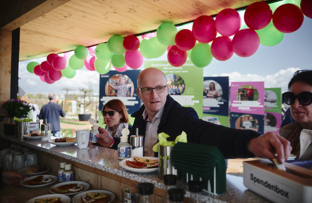 Eventfoto von Christoph Bastert: Besucherinnen und Besucher am Stand der LandFrauen auf der BUGA Mannheim 2023, mit Speisen, Getränken, Spendenbox und farbenfroher Dekoration.