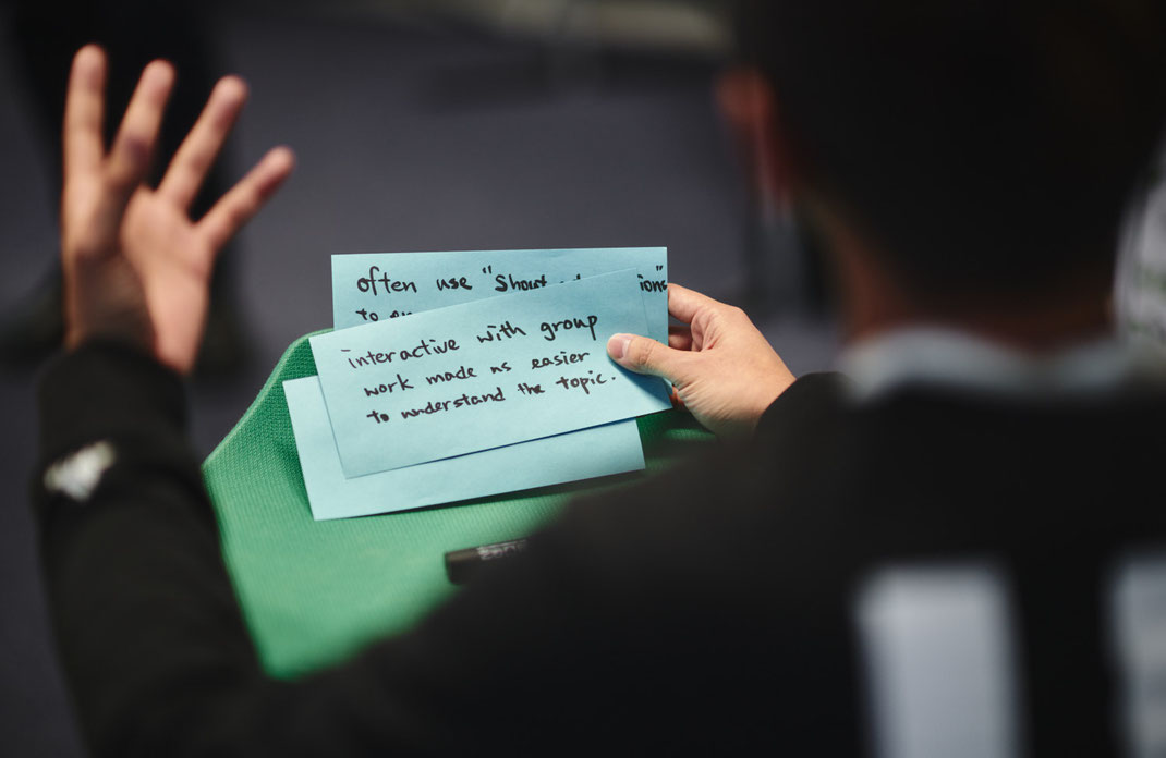 Teilnehmender des Mercedes-Benz Global Trainings in Stuttgart hält zwei blaue Moderationskarten mit handschriftlichen Notizen zum interaktiven Lernen in Gruppenarbeit. Foto: Christoph Bastert.