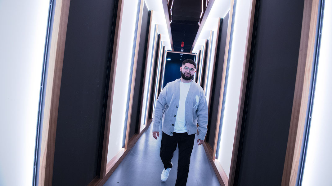 Das Foto zeigt einen jungen Manager in einem Flur mit vertikalen lichtern, sehr stylisch