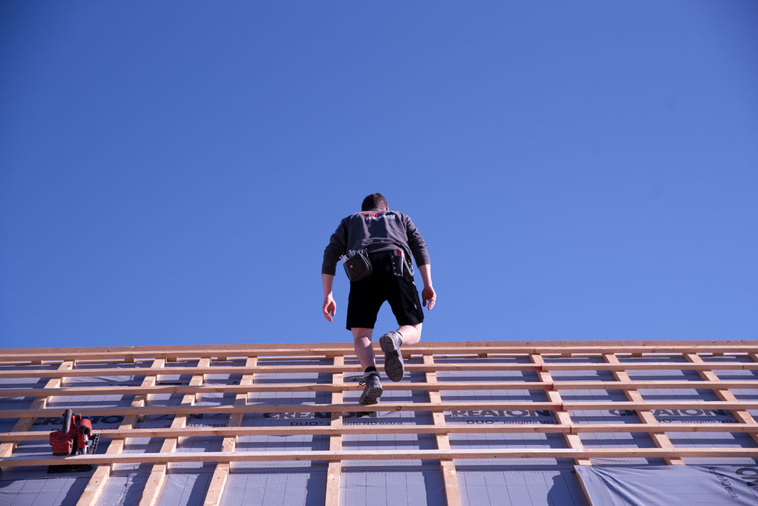fotografie hausbau handwerker, mitarbeiter läuft auf dachbalken