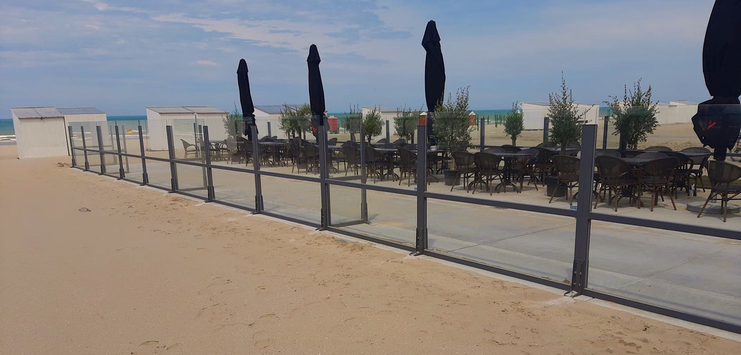Windschutz-System der Baureihe Monaco als stabile Terrassenabgrenzung am Strand als robuster Wetterschutz für die Außengastronomie