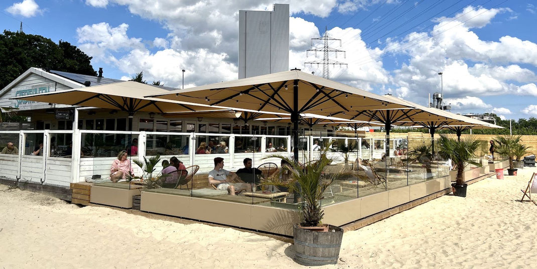 Windschutz-System Casablanca kombiniert mit großen Gastronomie-Schirmen in einer Beach-Bar