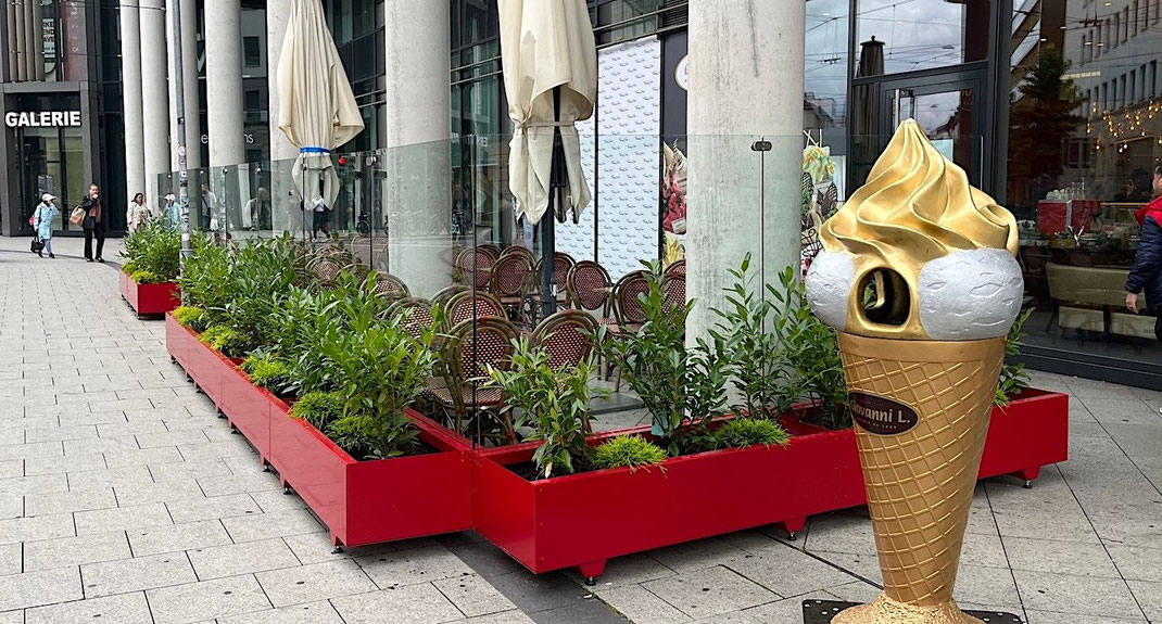 Gastronomie-Windschutz in Farbe rot Modell Casablanca mit integrierten Pflanzkästen und Glaselementen auf einer Café-Terrasse