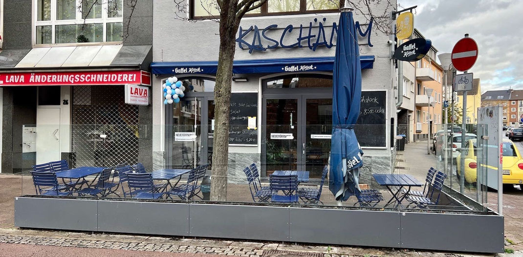 Mobile Windschutz-Elemente in Anthrazit kombiniert mit blauer Gastronomie-Bestuhlung in der Innenstadt 
