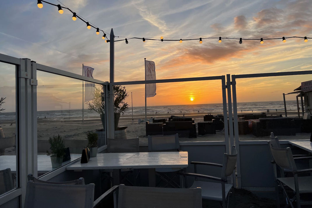 Stabile Windschutz-Anlage in der Strandgastronomie direkt an der Nordsee, schützt Gäste vor Meeresbrise bei freiem Blick auf das Meer und den Sonnenuntergang