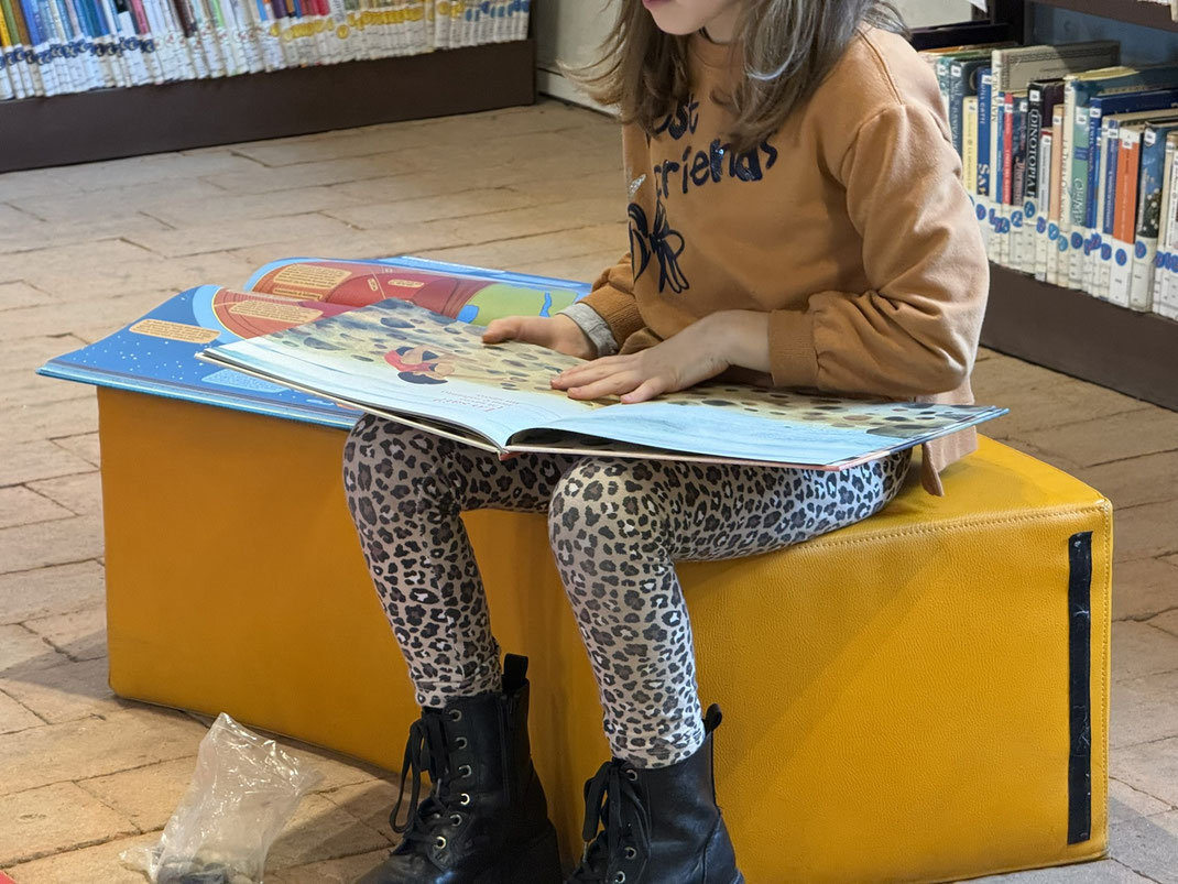 Bambina che osserva un libro di non fiction illustrato