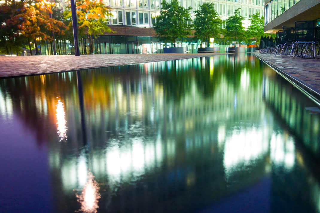 Wasserfläche mit Spiegelungen der umliegenden Gebäude