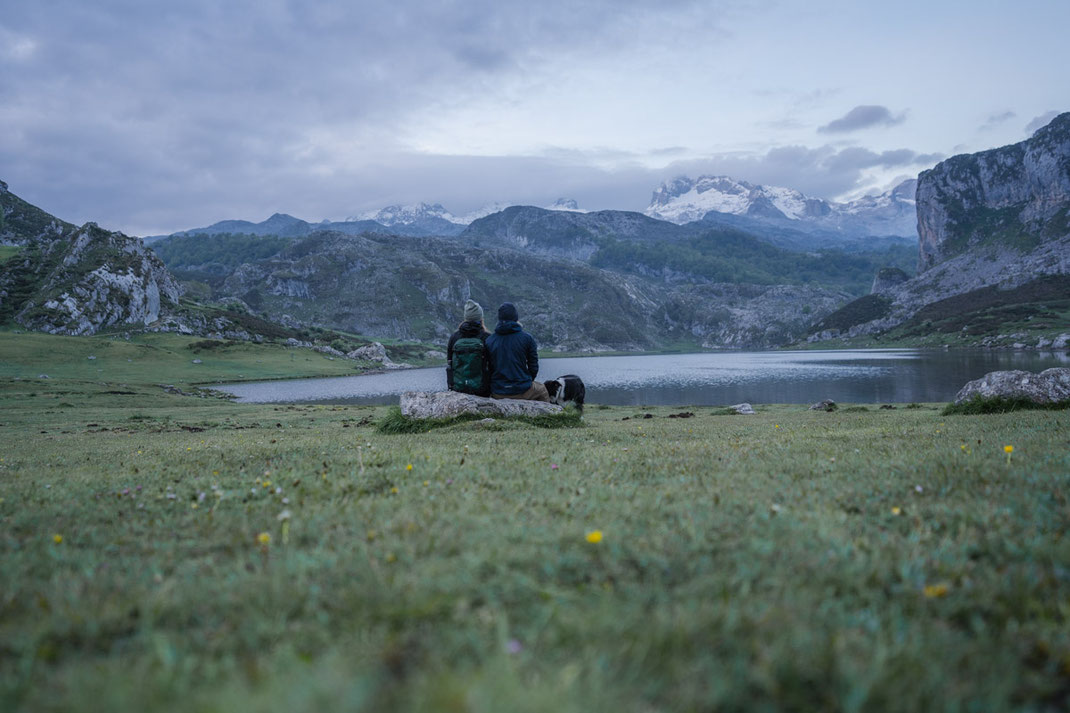 Ein Paar sitzt auf einem Stein und blickt auf den See im Nationalpark Picos de Europa.