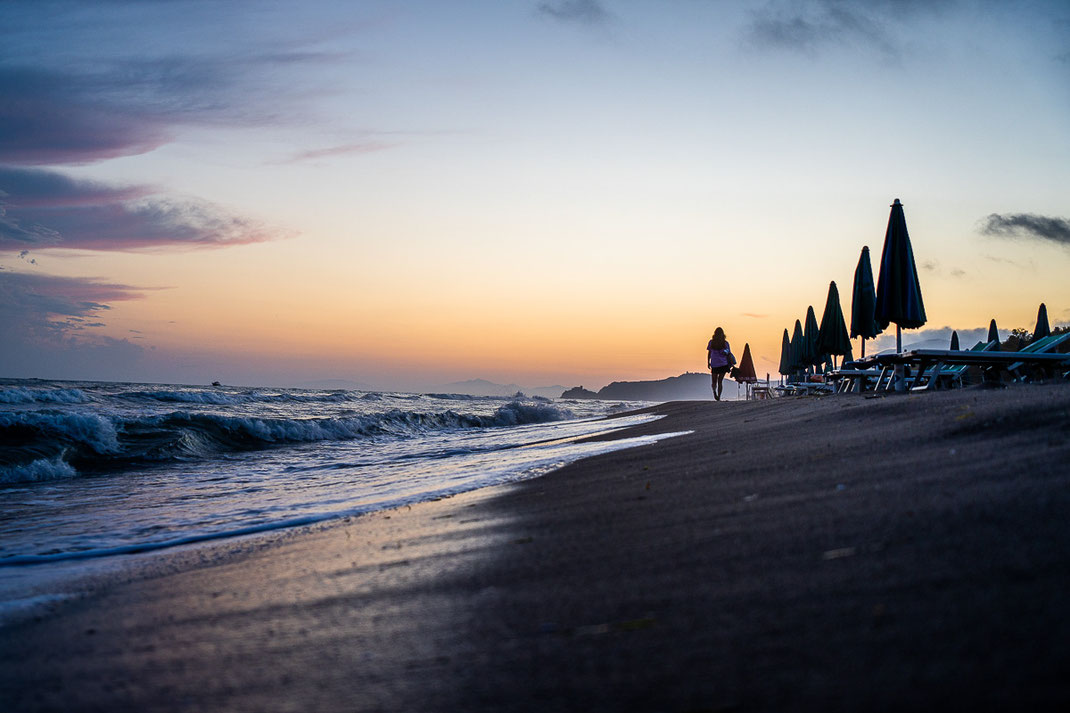 Frau schlendert am verlassenen Strand bei Castiglione della Pescaia entlang.