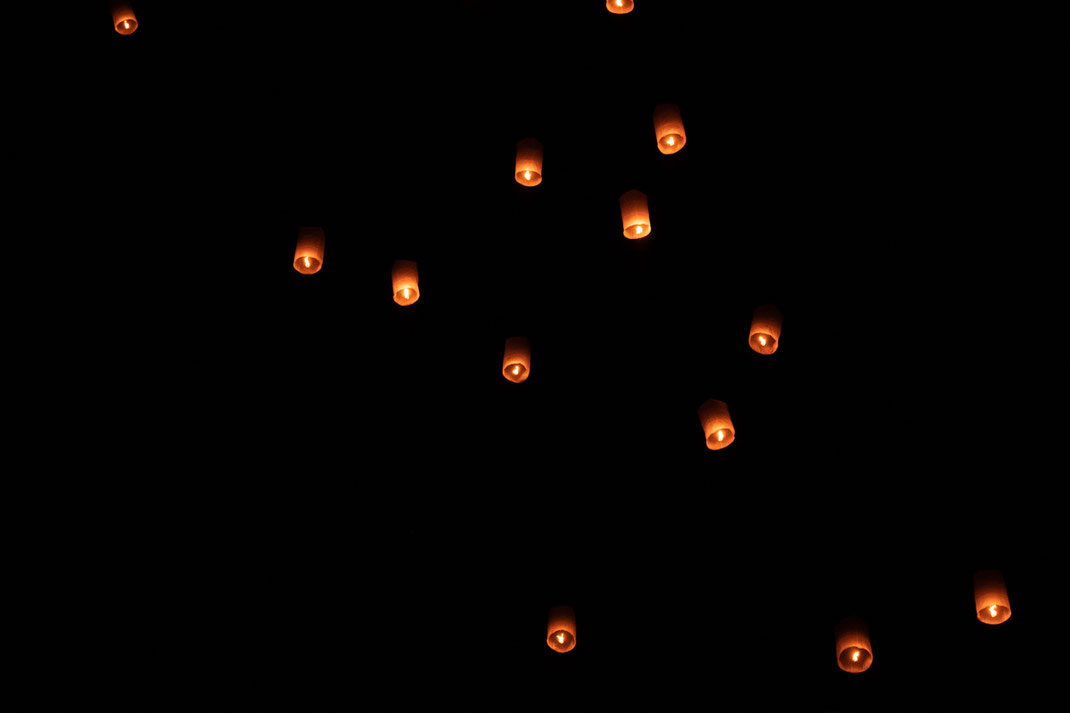 Des lanternes célestes individuelles s'élèvent dans le ciel nocturne près de Sukhothai.
