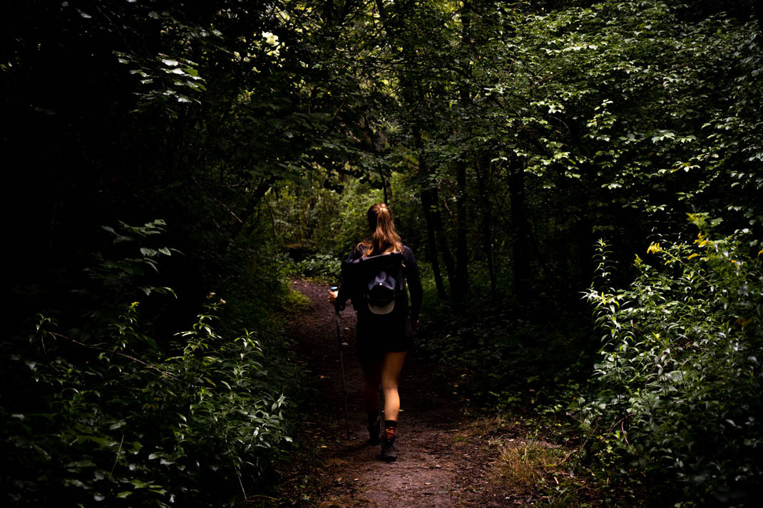 Frau wandert durch finsteren Wald.