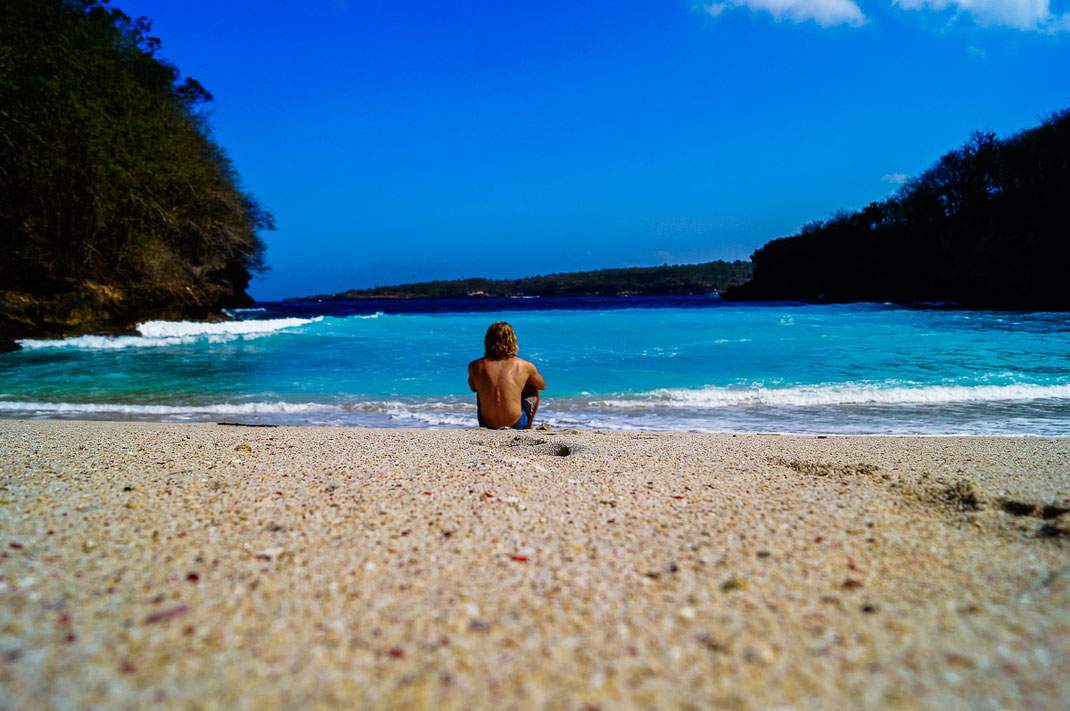 男子孤独地坐在沙滩上眺望大海。