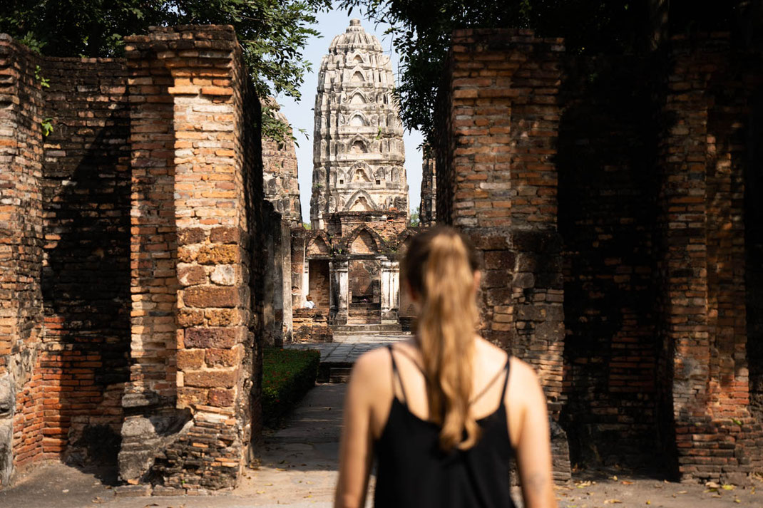 Eine Frau schlendert durch die Ruinen im historischen Park in Sukhothai.