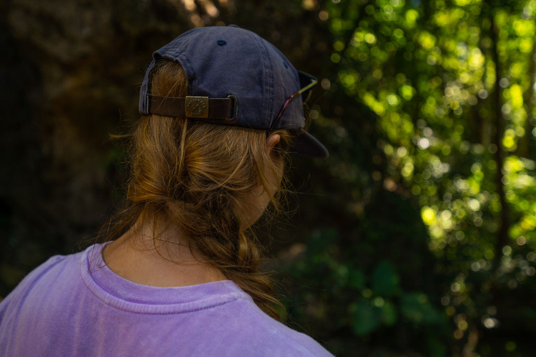 グリーン・ジャングル・パークで、茶髪で帽子をかぶった女性が地面を見下ろしている。