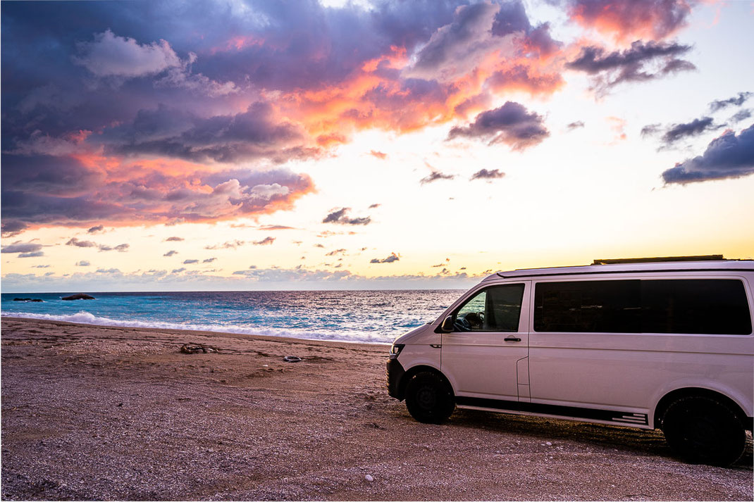 Sonnenuntergang am Kathisma Beach mit weißem VW Bus im Vordergrund.