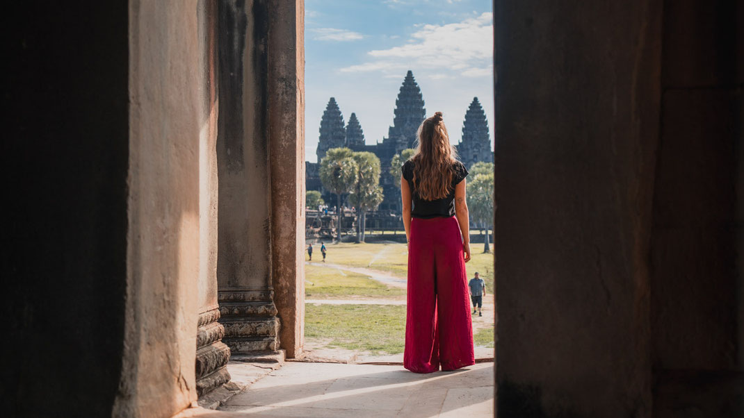 A woman in red pants looks at the Angkor Wat.