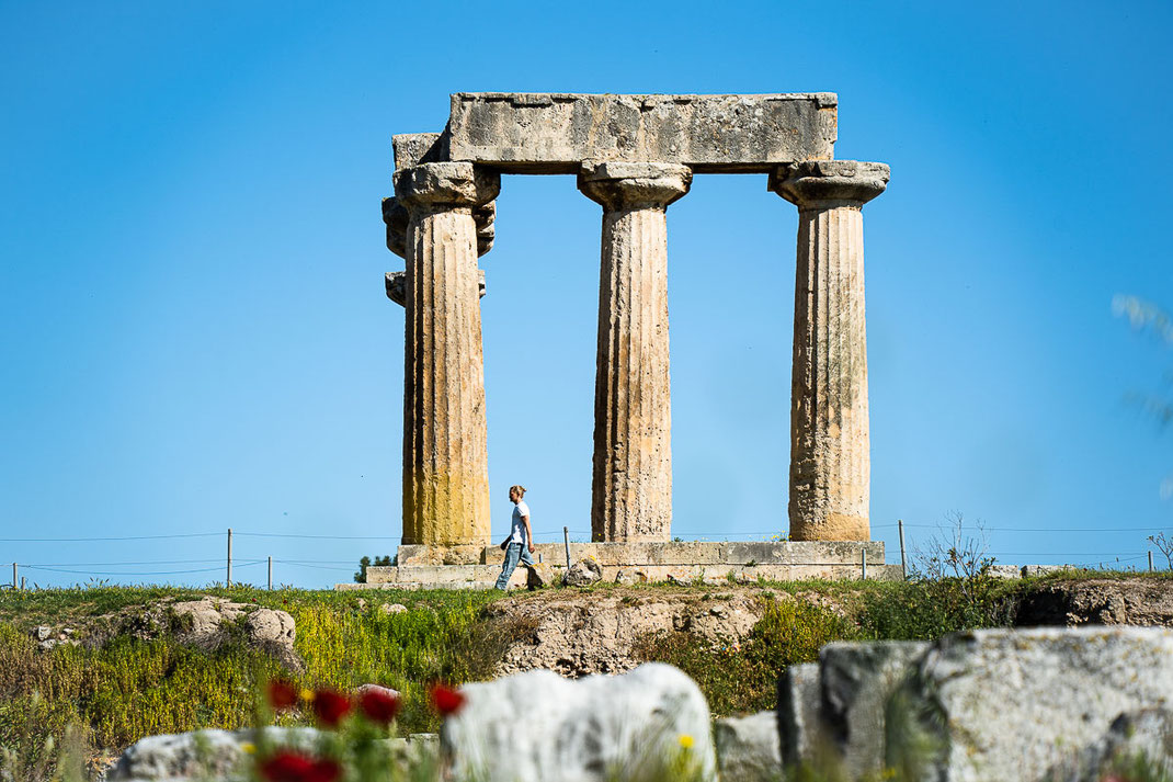 Ein Mann schlendert an den antiken Säulen des Apollon-Tempels in Korinth vorbei.