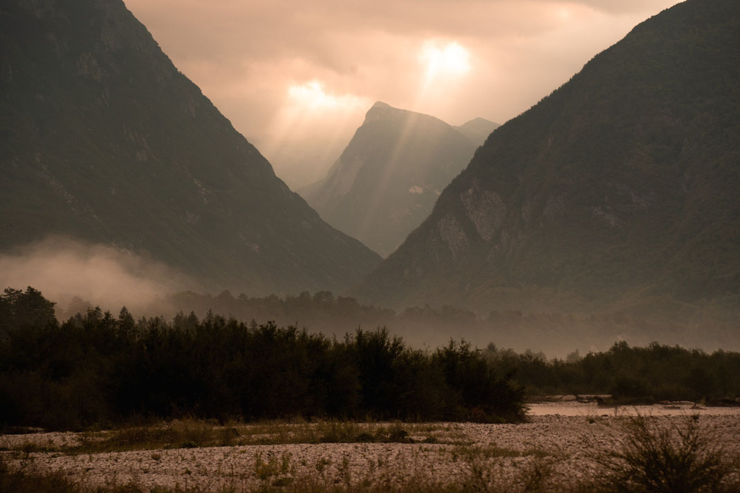 Malerischer Sonnenaufgang im Soča Tal mit Nebel und Sonnenstahlen.