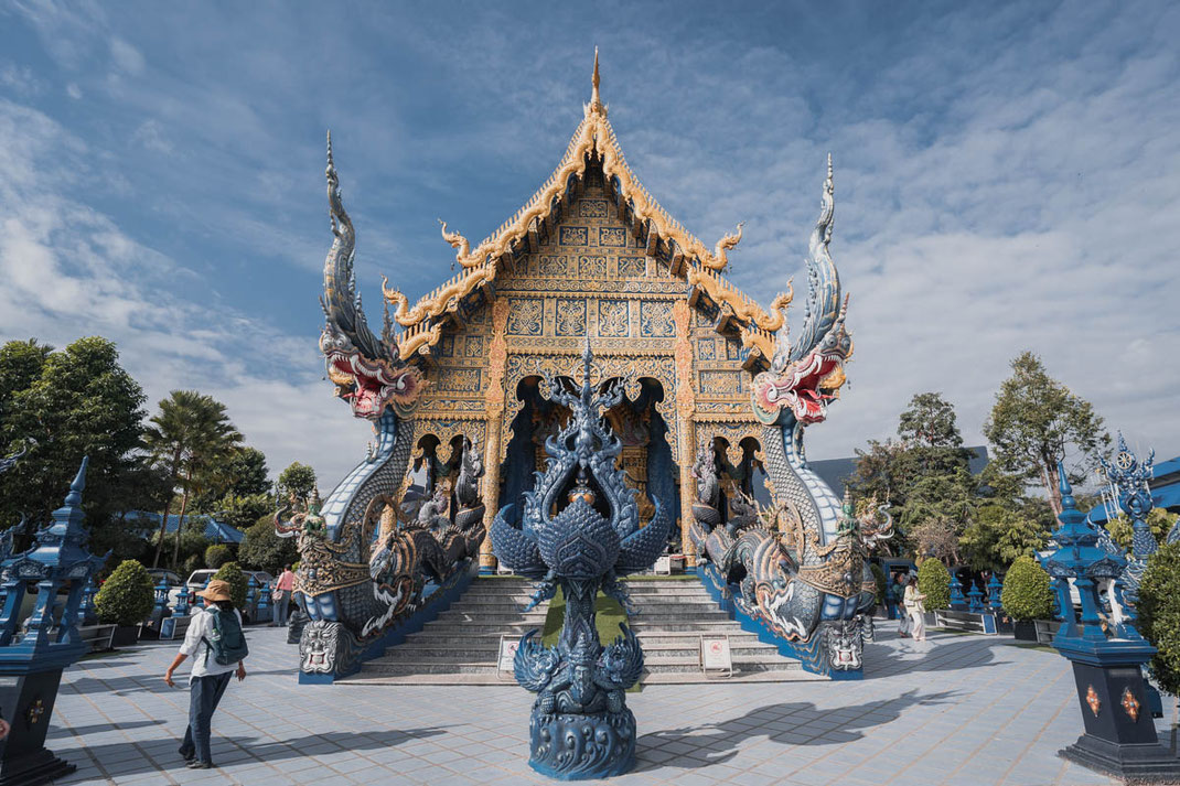 Das blaue Hauptgebäude verziert mit unzähligen goldenen Elementen im Wat Rong Suea Ten.