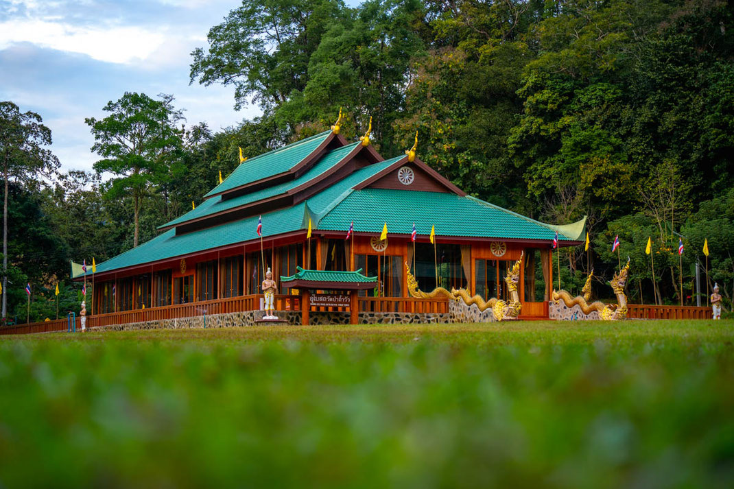 Ein großer buddhistischer Tempel mit Dschungel im Hintergrund.