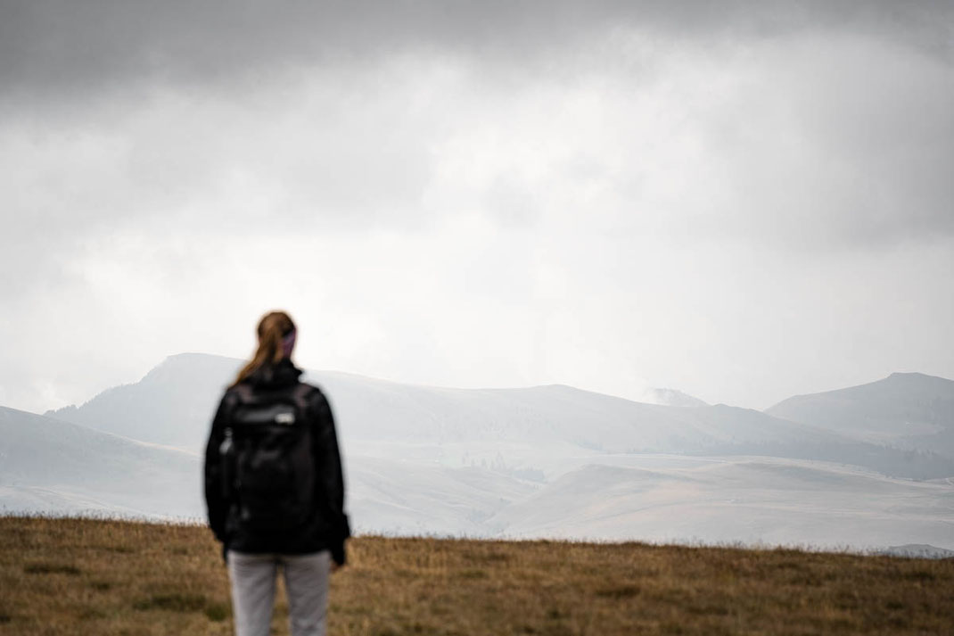 Eine Frau steht auf einer Wiese und genießt den Ausblick auf die Landschaft im Bucegi-Nationalpark.